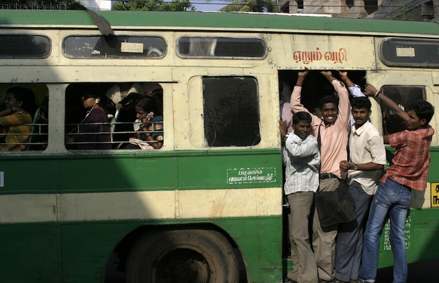 A densely packed bus in Chennai with some people even hanging onto the doorway