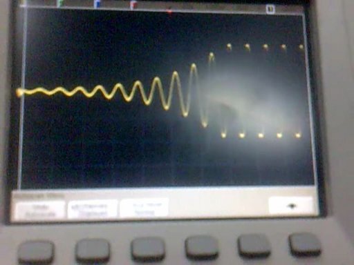 An exponentially increasing and eventually stabilizing sine wave shown on an oscilloscope